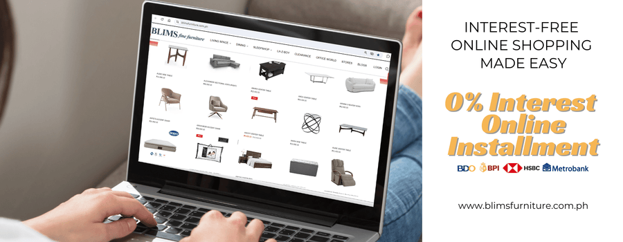 Person using a laptop on a sofa with an online furniture shopping website displayed.