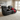 Black leather recliner sofa with a red pillow and blanket in a living room setting.